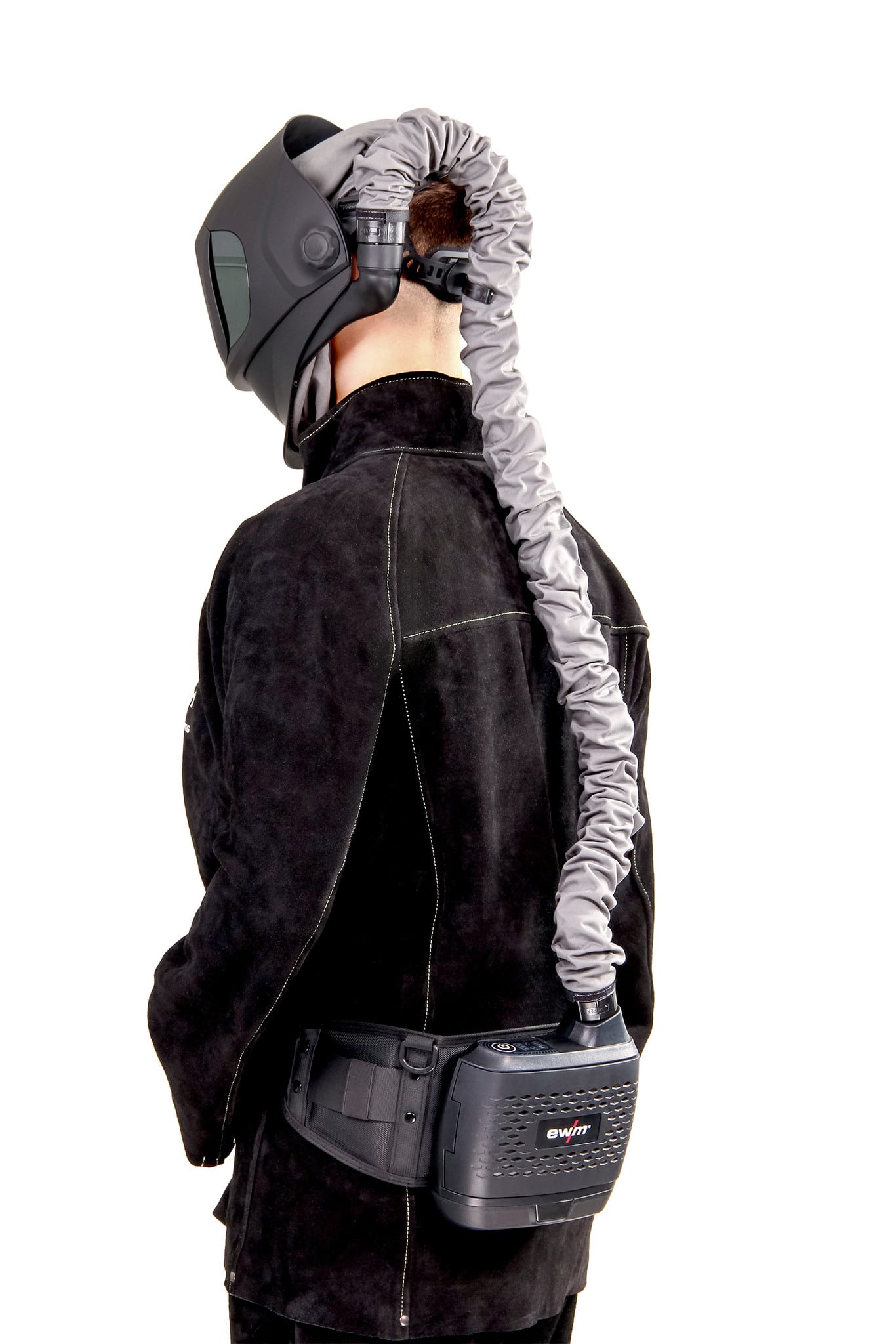 En person iklädd Svetshjälm friskluft EWM Powershield Guardian Clean Set, en svart skyddshjälm med en flexibel slang kopplad till en midjemonterad enhet, sedd bakifrån och klädd i svart jacka.